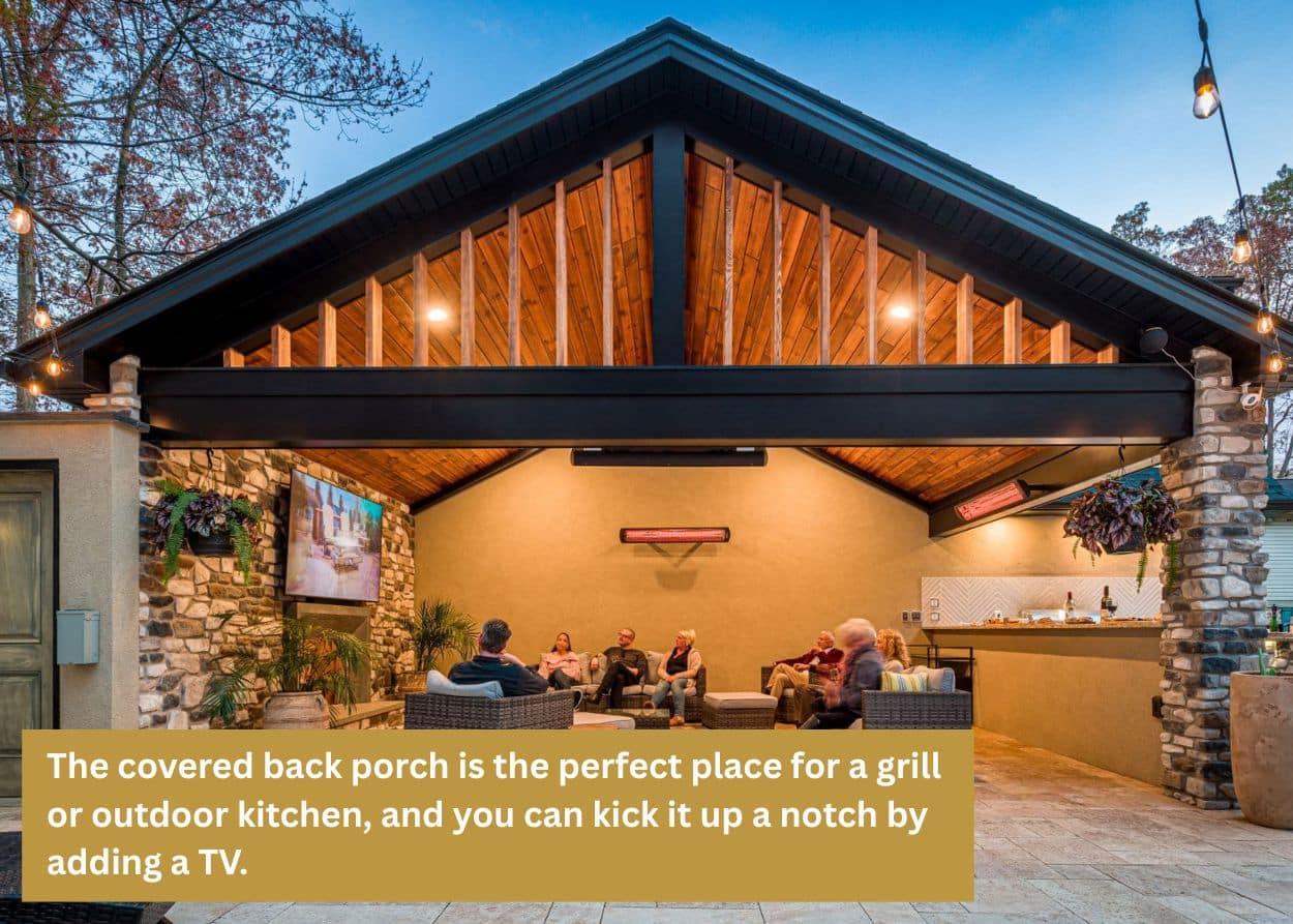 Outdoor pavilion-style seating area with stone walls, wood ceiling, and built-in entertainment space at dusk. Caption: The covered back porch is the perfect place for a grill or outdoor kitchen, and you can kick it up a notch by adding a TV.