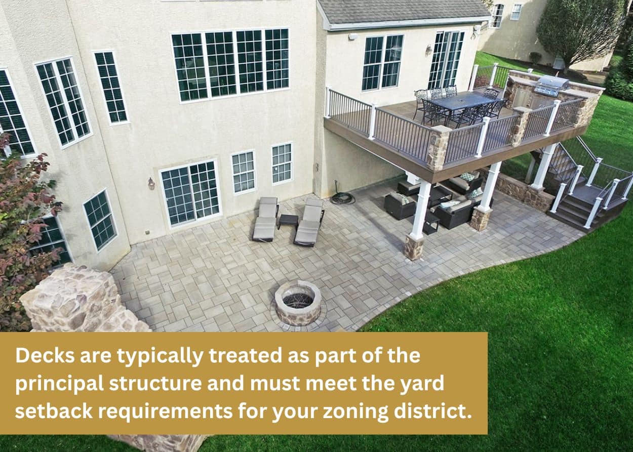 Backyard patio with elevated deck, outdoor dining area, and stone fire pit.