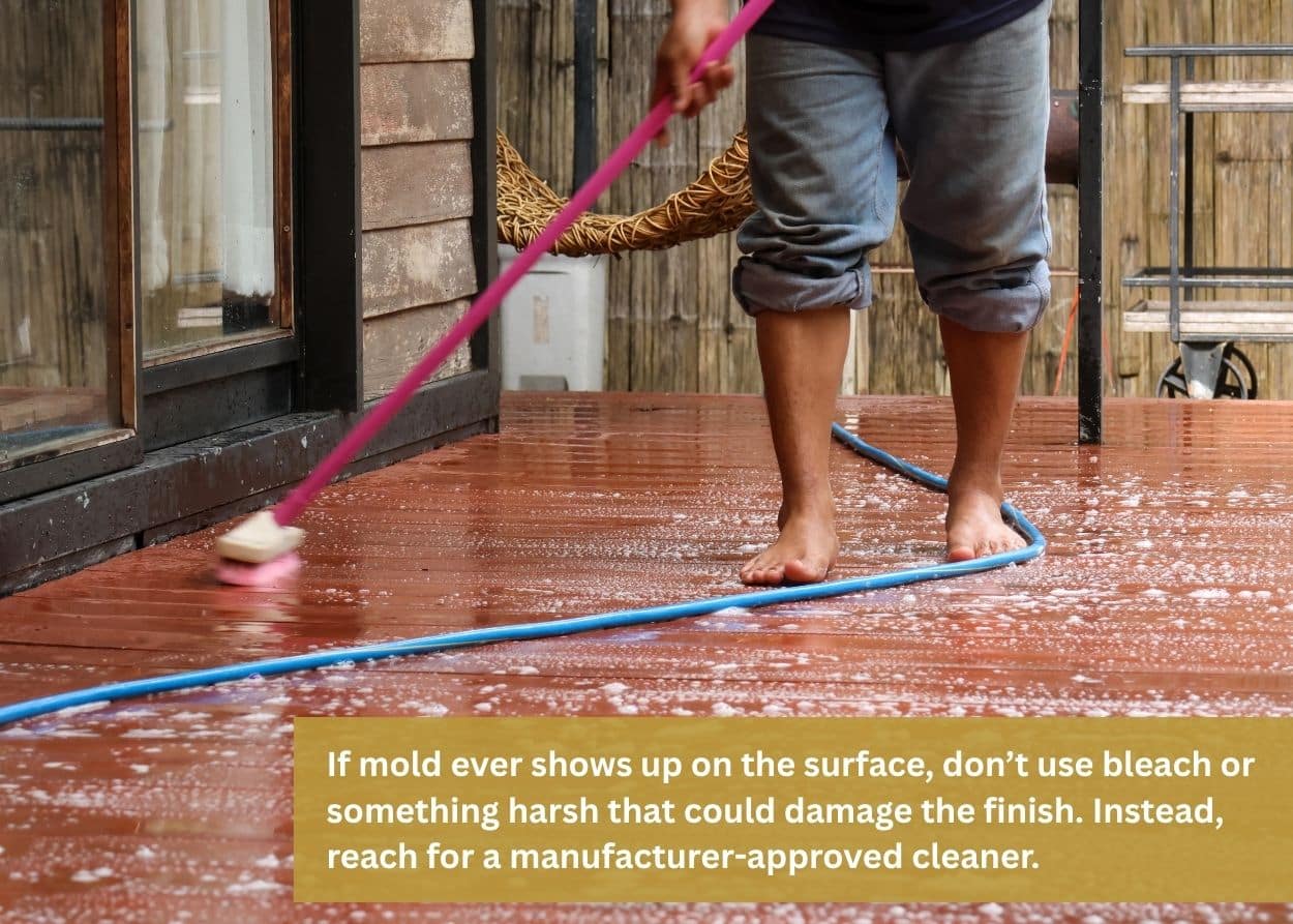 Person scrubbing and cleaning deck boards with soap, water, and a brush.
